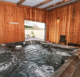 An indoor wooden room with a hot tub and two black chairs at Y Felin - Celyn in Borth