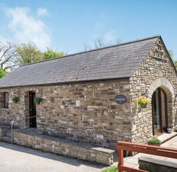 A stone cottage with a slate roof and hanging flower pots at Highbury in Spittal near Haverfordwest