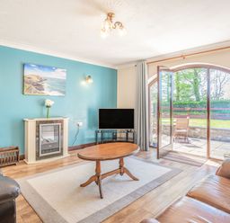 A living room with a wooden coffee table two leather sofas a TV and a fireplace at Highbury in Spittal near Haverfordwest