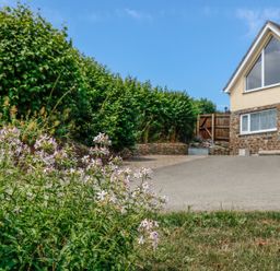 A garden with flowers and bushes next to a detached house with stone and yellow walls at Treview in Launceston