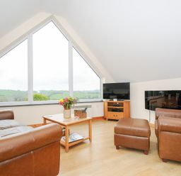 A living room with brown leather sofas a wooden coffee table a flat screen tv and large triangular window at Treview in Launceston