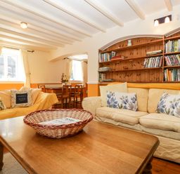 A living room with sofas cushions a wooden coffee table bookshelf and a dining table with chairs at The Pound in Trellech near Monmouth