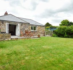 A stone house with a patio table and chairs and a lawn at Shepherds Rest in Jacobstow near Bude