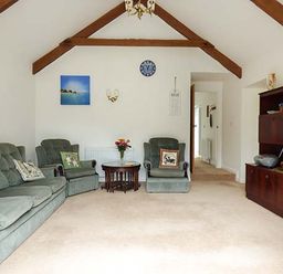 A living room with green sofas wooden beams and a wooden cabinet at Shepherds Rest in Jacobstow near Bude