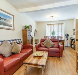 A living room with two red leather sofas a wooden coffee table and a dining table by the window at Dringarth in Tenby