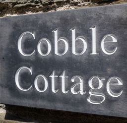 A stone engraved sign with the words Cobble Cottage