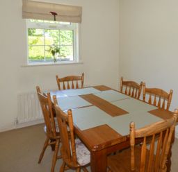 A dining room with a wooden table and six chairs and a window with a flower vase at Woodbine Cottage Old Leighlin near Kilkenny County Kilkenny