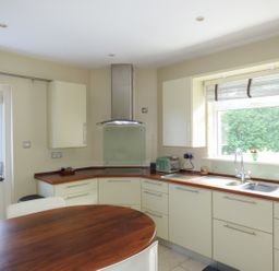 A kitchen with cream cabinets wooden countertops a stainless steel range hood a toaster kettle and a window with a blind at Woodbine Cottage in Old Leighlin near Kilkenny County Kilkenny