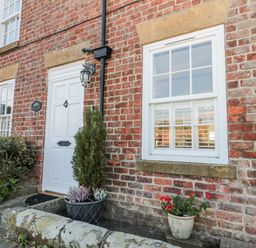 An outdoor view of a brick exterior with a door and windows at Croft View in Fylingthorpe near Robin Hood's Bay