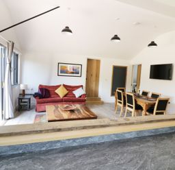 An open living and dining area with a red sofa and wooden table at Whitehands Farm Barn in Old Buckenham