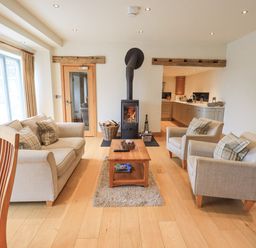 A living room with a wood stove sofa armchairs and a coffee table at Lime Cottage Backbarrow near Newby Bridge