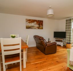 A living room with dining table chairs leather sofa and television at Foxes Meadow in Howey near Llandrindod Wells