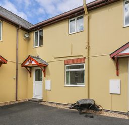 The exterior of connected houses with beige walls white doors and windows and small roofs above doors at Pheasant Wood in Howey near Llandrindod Wells