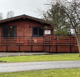 A cabin with a deck and sliding door at Wildcat Lodge in Newtonmore