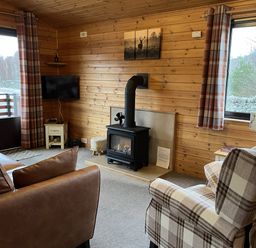 A living room with a fireplace and television at Wildcat Lodge in Newtonmore