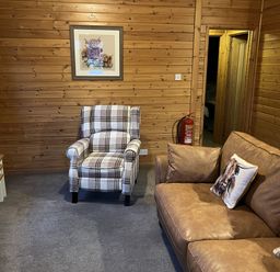 A living room with an armchair and a sofa at Wildcat Lodge in Newtonmore