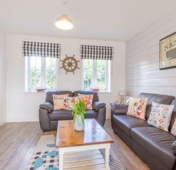 A living room with two leather sofas and a wooden coffee table with flowers at Lilipad Cottage The Bay near Filey