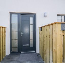 A front door with glass panels and wooden railing with a sign saying The Beach Halt in Perranporth
