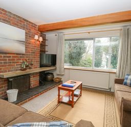 A living room with two brown sofas a wooden coffee table and a brick fireplace at Swan Dyke Cottage Horning near Wroxham