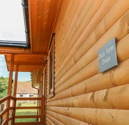 A wooden porch with railing and a sign that reads Chale Farm Lodge at Chale Farm Lodge in Chale