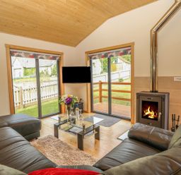 A living room with leather sofas a glass coffee table a fireplace and sliding doors at Chale Farm Lodge in Chale
