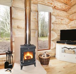 A room with a wood burning stove firewood basket television and large windows at Heron Lodge in North Kessock