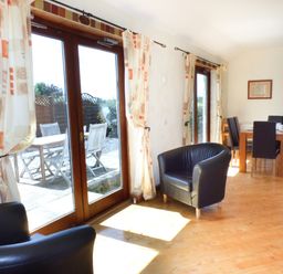 A dining area with table and chairs and black armchairs near glass doors with patterned curtains at The Old Granary in Spittal