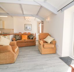 A living room with two armchairs and a sofa with cushions at The Cottage in Chilsworthy near Holsworthy