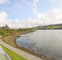A view of a shoreline with small boats on water and grassy hills at Ancarva Near Kingsands