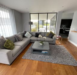 A living room with a gray sectional sofa, a gray area rug, a gray coffee table with a plant, and a floor lamp at Ancarva Near Kingsands