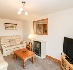 A living room with beige sofas wooden coffee table television and a fireplace at The Hayloft in Milton near Brampton