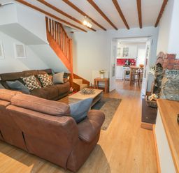 A living room with two brown sofas a wooden coffee table wooden floors stairs and a stone fireplace at Tryfan in Llanberis