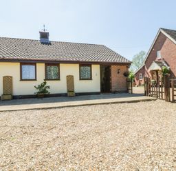 A single story house with tiled roof and three windows beside a gravel driveway at Kingfisher in Wattisfield near Rickinghall and Diss