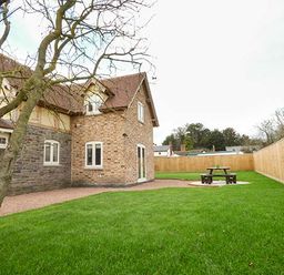 A fenced garden with a picnic table and a tree beside a brick house at Rose Cottage in Winforton near Hay-on-Wye