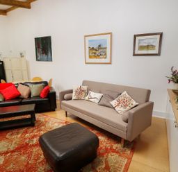 A living room with two sofas pillows coffee table and framed paintings at View The Gallery in Okehampton