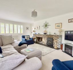 A living room with a fireplace and seating at Kilcarreg in Rock near Wadebridge