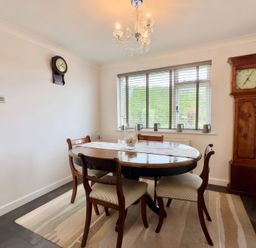 A dining room with a round table and clocks at Kilcarreg in Rock near Wadebridge