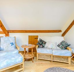 A room with a chair and a sofa with cushions and a small wooden table between at The Bothy in Phocle Green near Ross-on-Wye