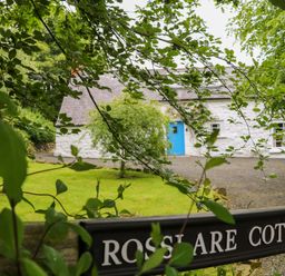 A cottage with a blue door and garden at Rosslare Cottage in Broughshane