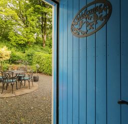 A garden with a table and chairs viewed through a blue door at Rosslare Cottage Broughshane