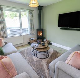 A living room with a fireplace and sofas at Yew - Woodland Cottages Bowness-On-Windermere
