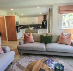 A living room with a sofa and kitchen area at Yew - Woodland Cottages Bowness-On-Windermere