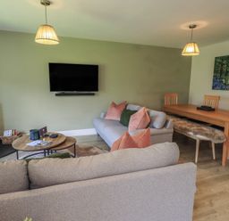A living room with a sofa and dining table at Yew - Woodland Cottages Bowness-On-Windermere