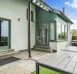An outdoor patio with stone steps and a table next to a white and green house at Beech - Woodland Cottages in Bowness-on-Windermere