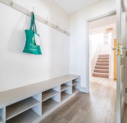 A hallway with a built-in bench and cubby storage a door leading to carpeted stairs at Beech - Woodland Cottages in Bowness-on-Windermere