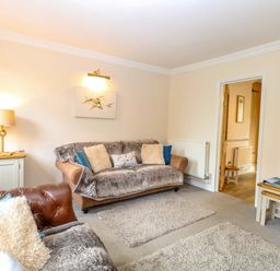 A living room with a sofa and lamp at Fern Cottage in Heacham