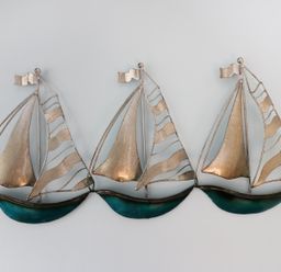 A metal wall decoration of three sailboats with silver sails and blue hulls at Number Fifteen in Withernsea