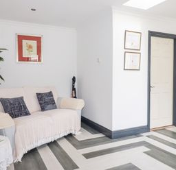 A living room with a sofa a plant framed pictures and a door leading to a bedroom at Chapel Green Studio Polgooth near St Austell