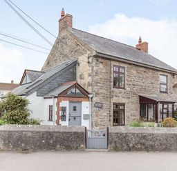 A stone cottage with a gray gate and garden at Victoria Cottage St Newlyn East near Newquay