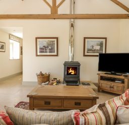 A living room with a wood stove tv and wooden coffee table at Cow Byre in Malton